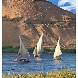 Egypt, Aswan, Nile River, Felucca sailboats, temple ruins and the large sand dunes