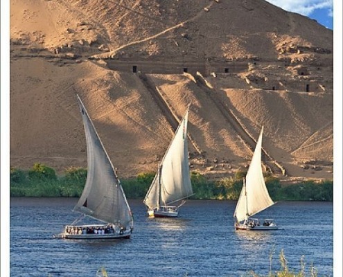 Egypt, Aswan, Nile River, Felucca sailboats, temple ruins and the large sand dunes